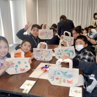 色や型を工夫して制作したミニトートバッグを手に笑顔の小学生