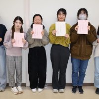 調査合宿の成果をまとめた中間報告書を持つ学生